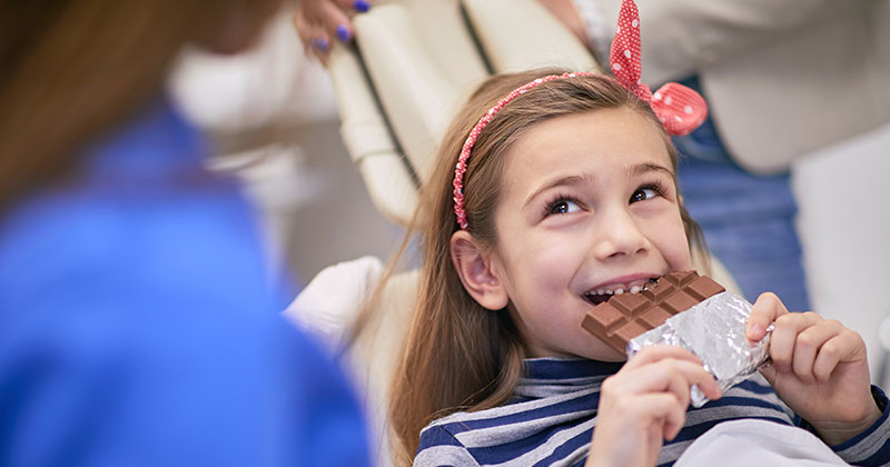 young girl in dentist chair eating chocolate