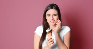 woman experiencing pain of sensitive after eating a cold icecream