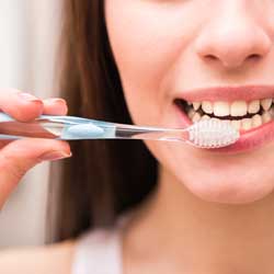 close up of woman brushing teeth with toothbrush