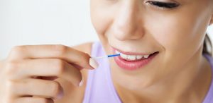 woman practicing gentle dental care by brushing between teeth with an interdental brush