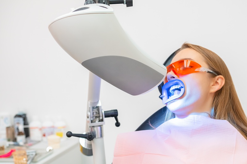 A female patient receives teeth whitening treatment,
