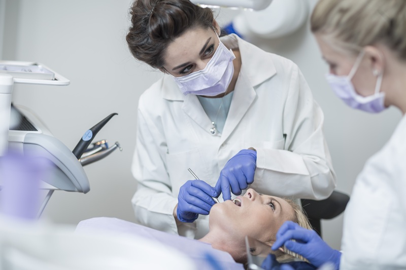 Female dentist examining patient with mouth mirror