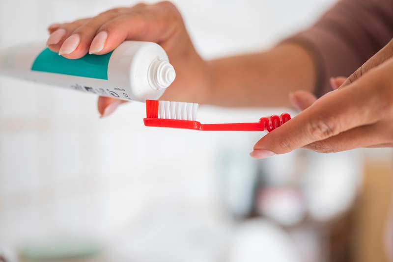 pair of hands holding toothbrush and toothpaste