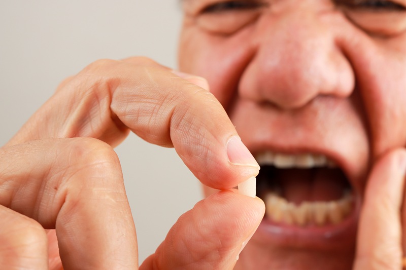Man holding up his chipped tooth between his fingers.