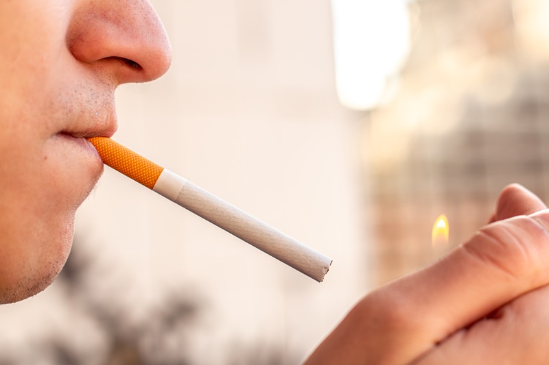 Smoking concept. Man lighting a cigarette with a lighter. Smoking a cigarette close-up.